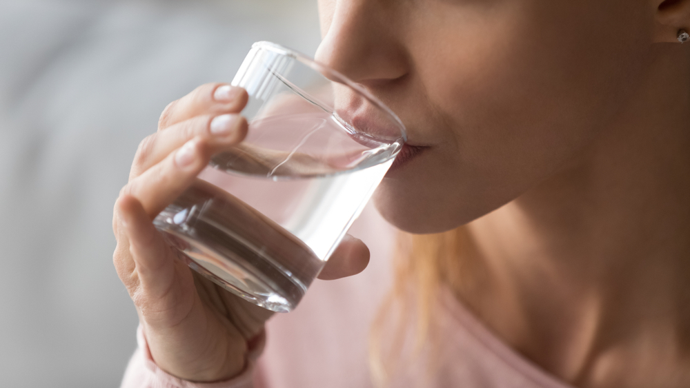 Close up cropped image thirsty woman holding glass drinks still water preventing dehydration, helps maintain normal bowel function and balance of body, skin and health care, healthy lifestyle concept
