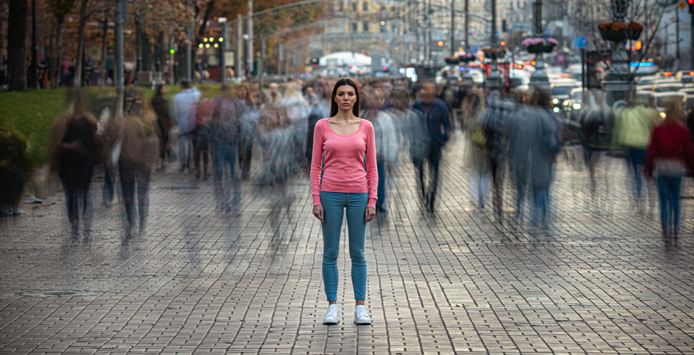 The young girl stands on the crowded urban street

