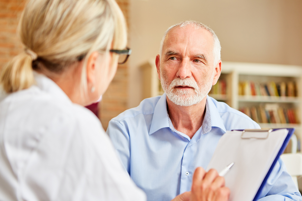 Senior patient listens to his doctor attentively during consultation
