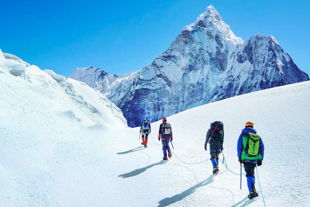 Group of climbers reaches the summit of mountain peak enjoying the landscape view in Nepal
