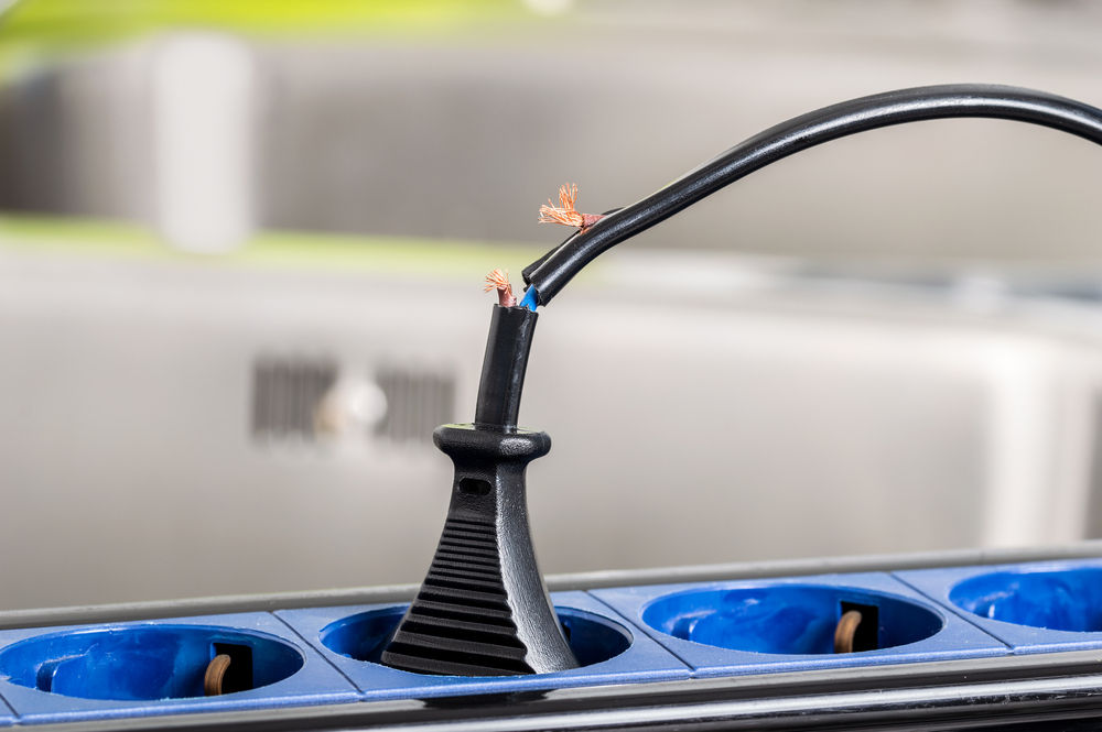 Close up of a dangerous damaged electrical cord a kitchen counter at home

