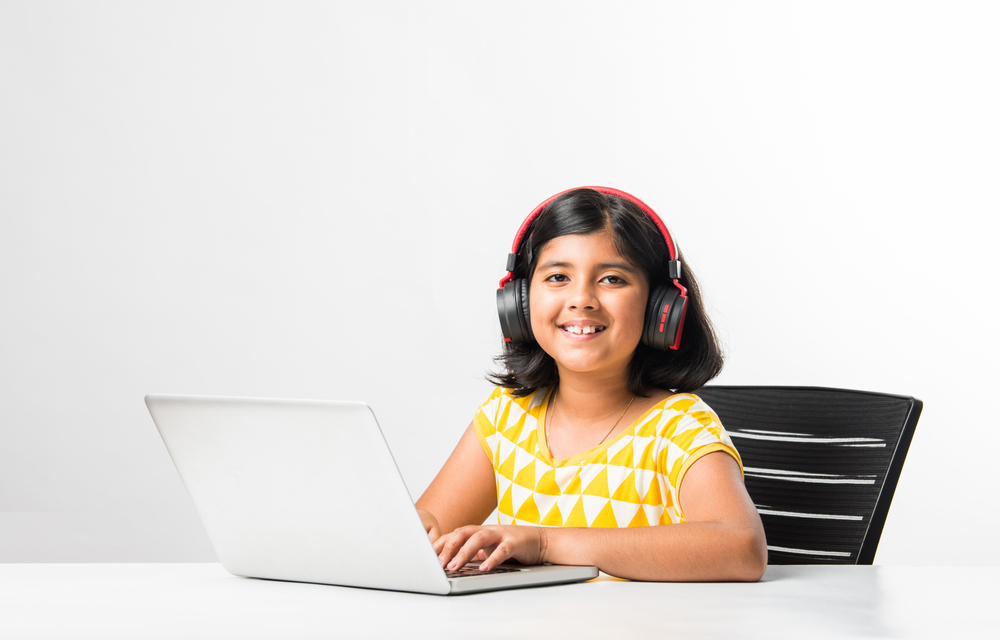 Pretty stylish Indian asian schoolgirl studying attending online lesson at home, social distance during quarantine, self-isolation, online education concept, home schooler