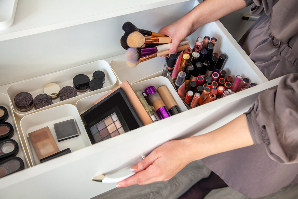 Woman hands is taking out makeup brush set from the drawer of vanity table. Concept of decluttering and organizing of beauty cosmetics and makeup kit with MUJI's PP makeup boxes. Copy space
