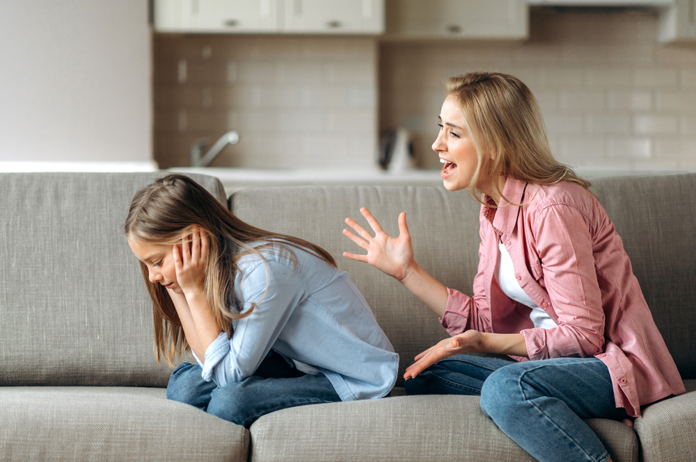Conflict of mom and daughter. Screaming mother, shouts at little daughter scolding her. Little girl is ignoring mom, close her ears with arms. Complicated relationships of mother and child