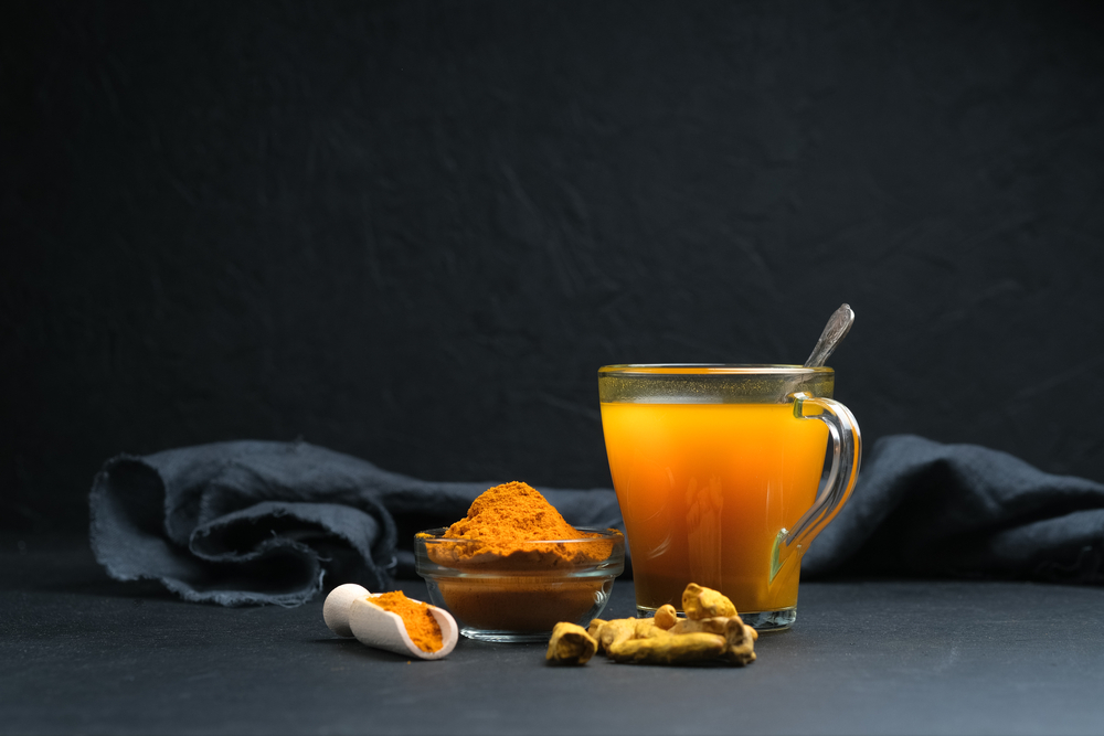 Turmeric tea with spices on a dark background with copy space.
