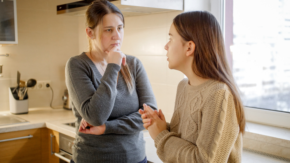 Young mother listening and talking to her teenage daughter complaining about problems and depression. Parent supporting and comforting child