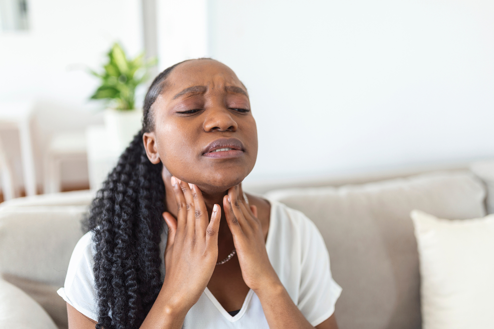 Close up of young woman rubbing her inflamed tonsils, tonsilitis problem, cropped. Woman with thyroid gland problem, touching her neck, girl has a sore throat
