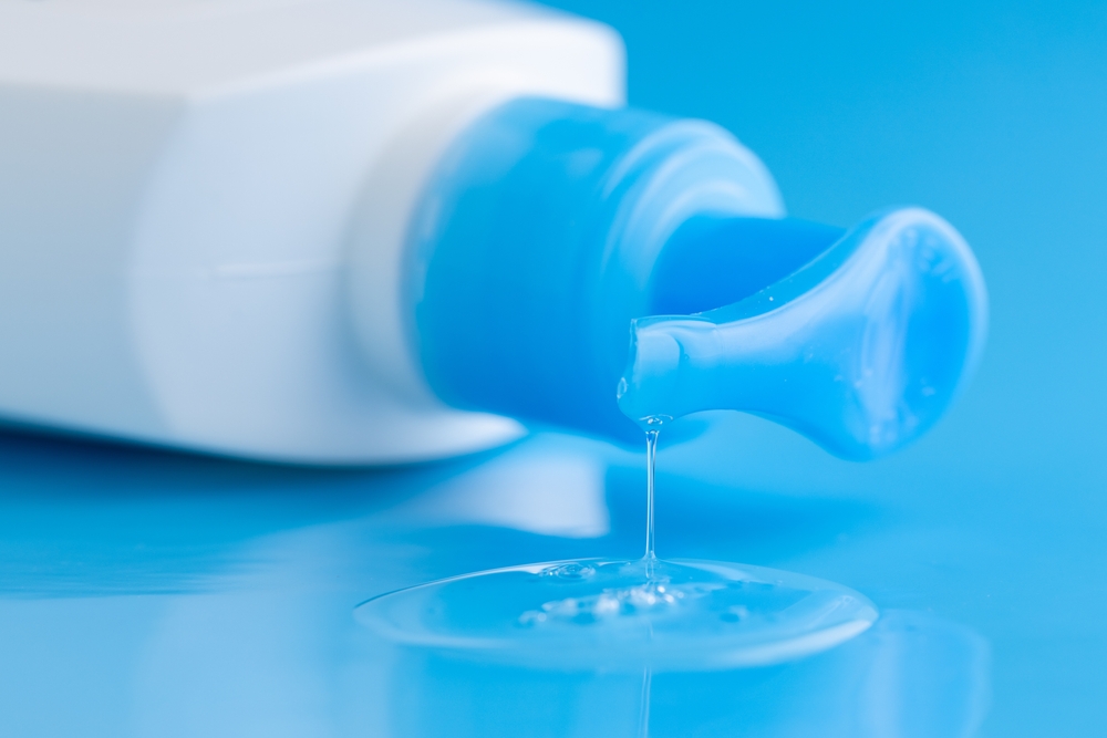 bottle of Intimate lubricant gel on blue. Intimate massage and comfortable sex consept. Cosmetic bottle.