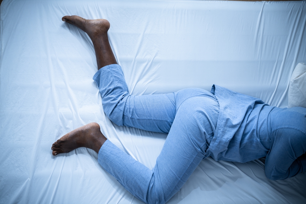 African American Man With RLS - Restless Legs Syndrome. Sleeping In Bed