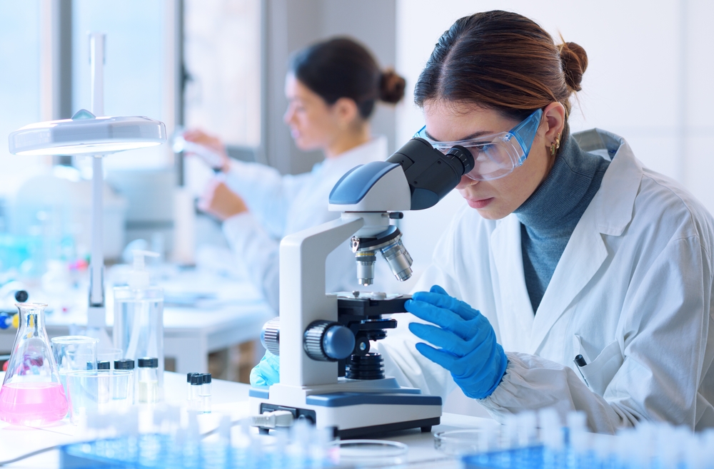 Young scientists conducting research investigations in a medical laboratory, a researcher in the foreground is using a microscope
