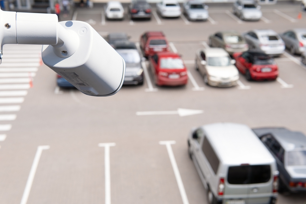 Technician installed IP CCTV camera hi-technology for look security area of work in car parking lot show signage with security cars park in area.

