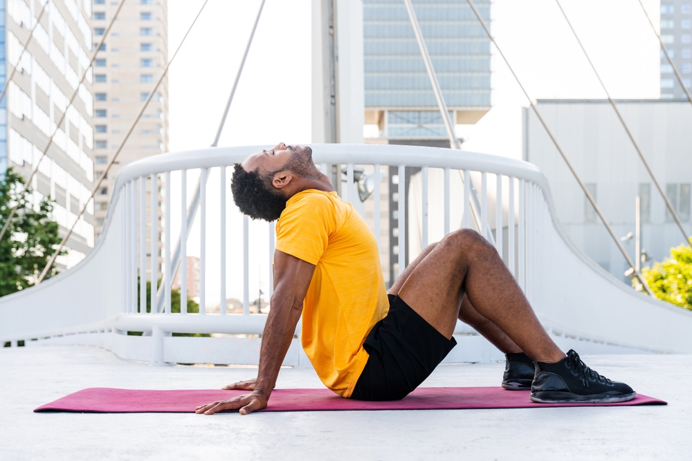 Black hispanic sportsman training outdoors in the city - African man with fit muscular body doing functional workout to train cardio, body muscles and abs core
