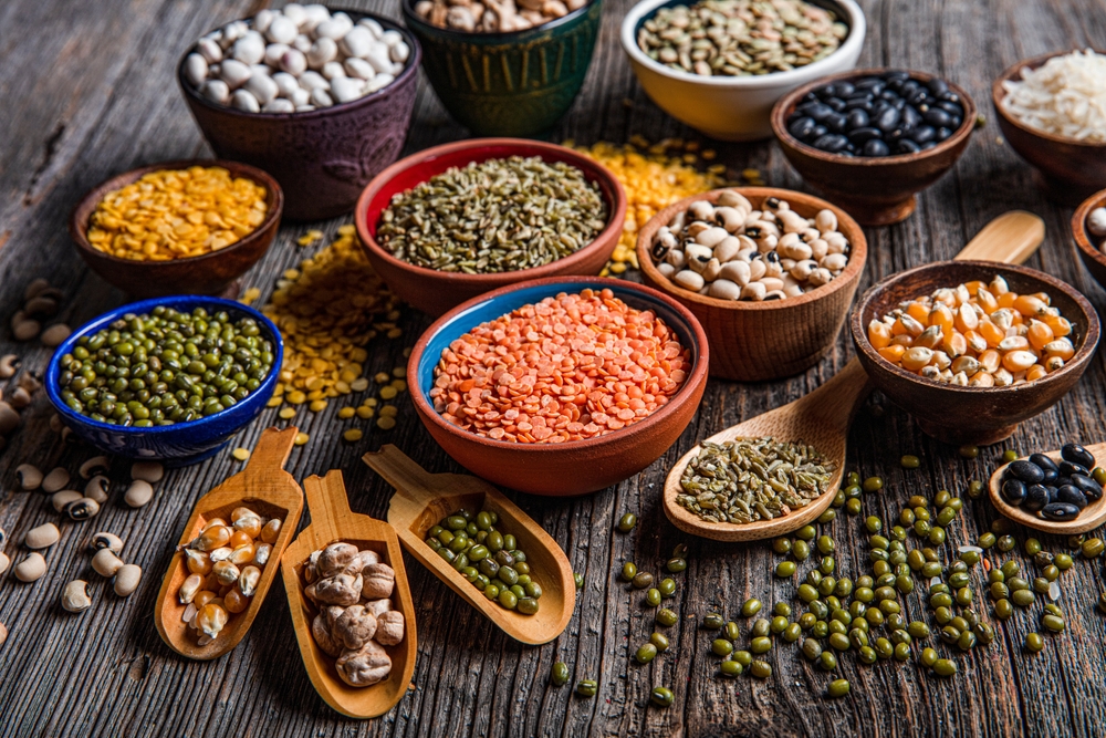Vegan protein source.Various assortment of legumes, lentils, chickpea and beans assortment in different bowls on wooden table. Top view.
