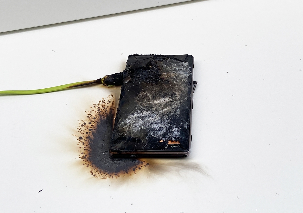 Mobile phone after battery explosion. Smartphone burn. Mobile phone caught fire. Mobile smartphone overheat and catch fire. Cable overheat and catch fire. Smartphone burn, bang, blast, blowing up.