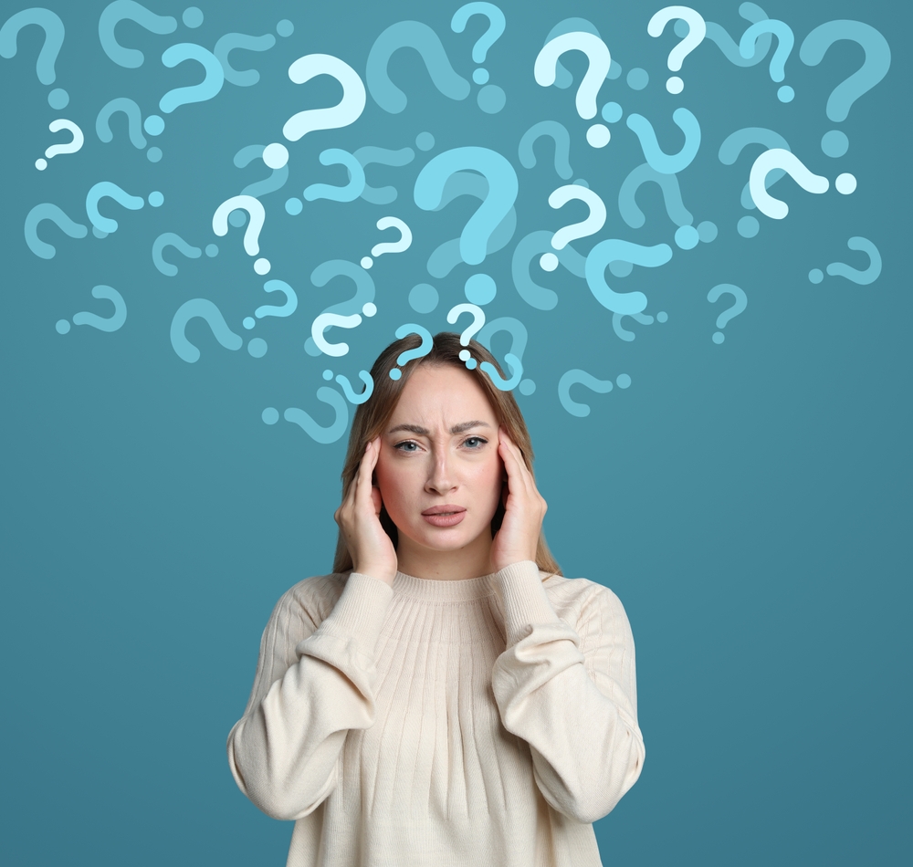 Amnesia concept. Woman trying to remember something on color background. Flow of question marks symbolizing memory loss