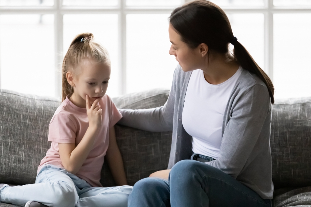 Serious mother talking to sad upset preschooler daughter kid at home. Mum consoling quiet girl, giving love, comfort, support, touching shoulder of child at home. Psychology, therapy, empathy concept