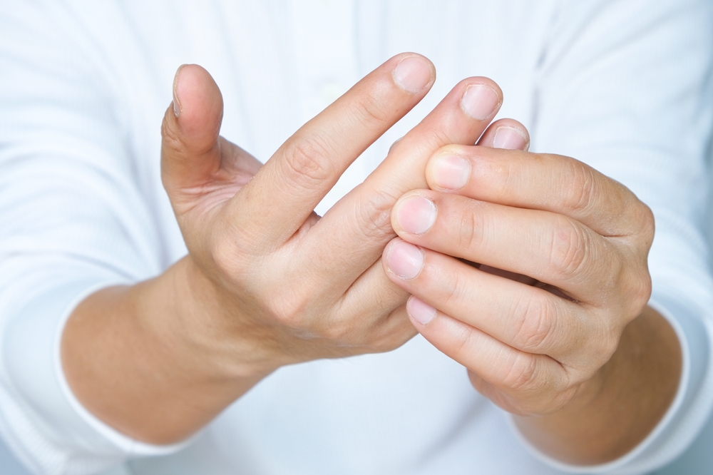Hand of man she massages his thumb and has finger pain, locked finger from work and office syndrome. on a white background medical concept