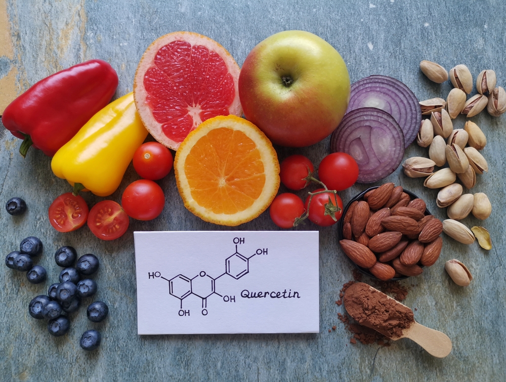 Structural chemical formula of quercetin with fresh fruit and vegetable. Quercetin is a plant pigment (flavonoid). It's found in many plants such as red onion, berries, tomato, nuts, citrus, apple...
