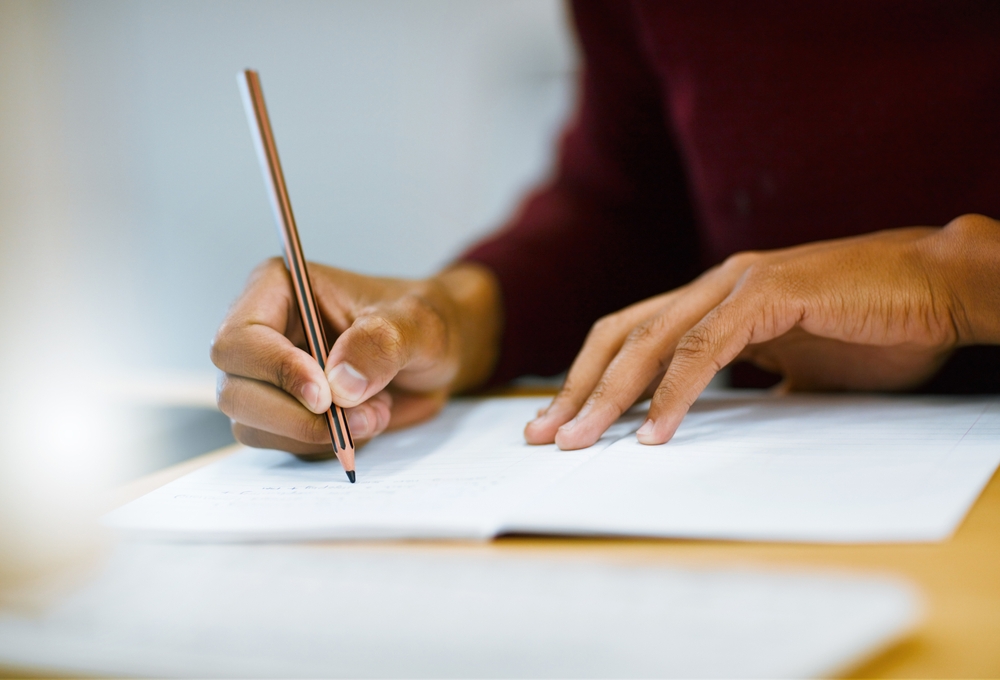 Writing, notebook and hands of person in library for university education, scholarship course or project research. Growth, studying and college student with notes, pencil and planning for exam.
