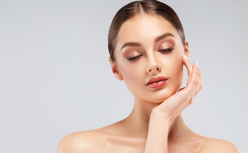 Beautiful young woman with clean fresh skin on face . Girl facial treatment . Cosmetology , beauty and spa .