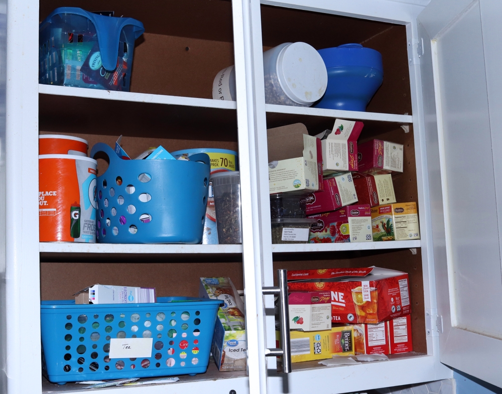 Dalton, OH USA - 07 15 2024: Open Double Cabinet in a Real Kitchen Tea Drink Mixes Containers Stuffed full and overflowing

