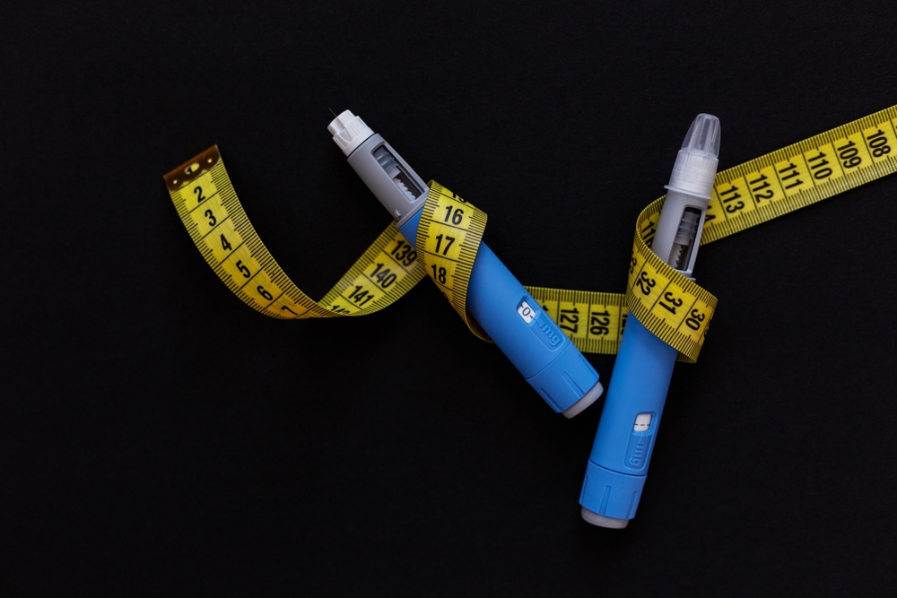 Drug injection ozempic with a yellow tape measure on a black background. Ozempic Insulin injection pen or insulin cartridge pen for diabetics. Medical equipment for diabetes parients.
