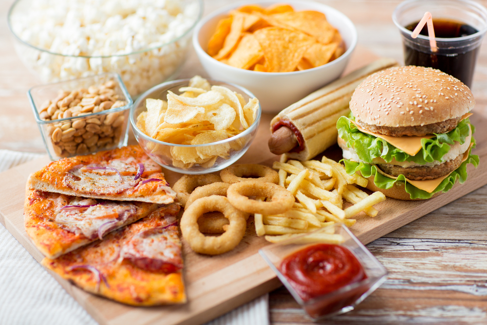 fast food and unhealthy eating concept - close up of fast food snacks and cola drink on wooden table
