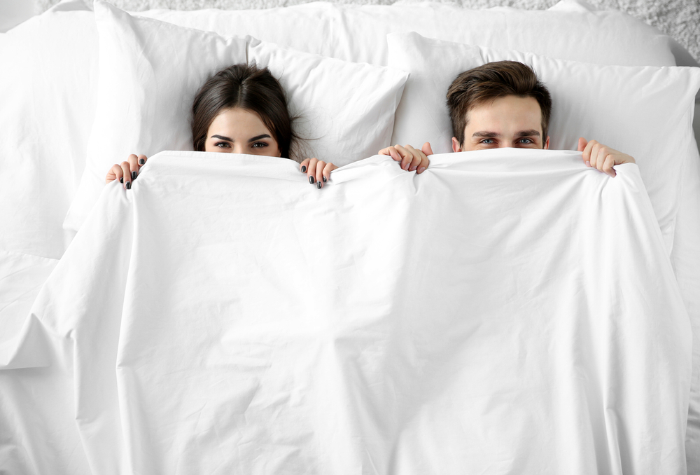 Young cute couple lying together in bed.