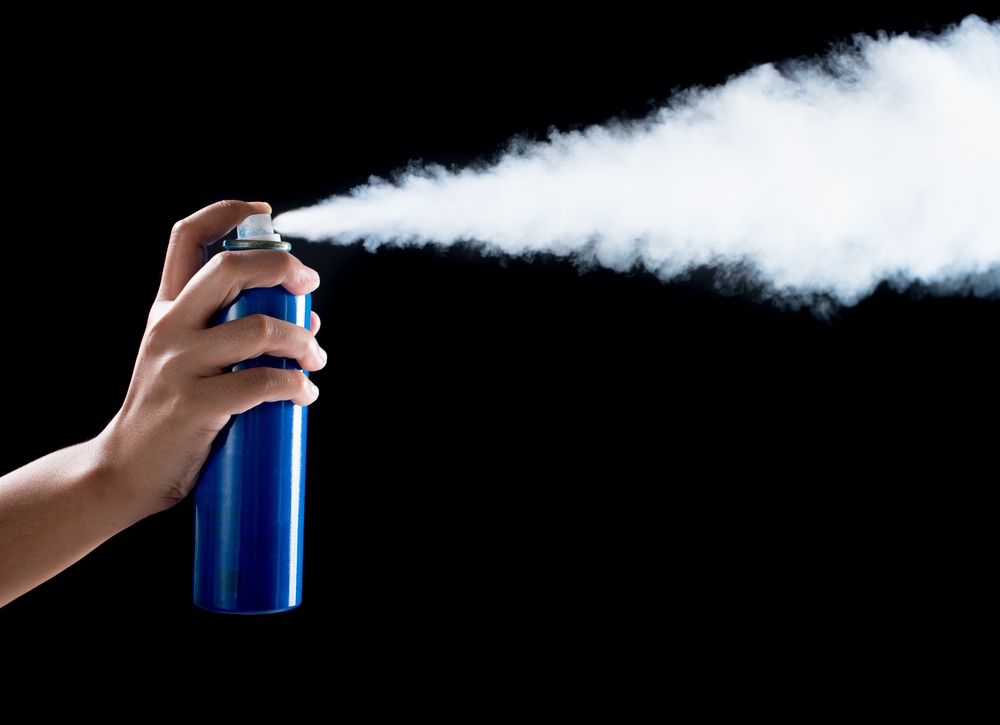 aerosol can spraying on black background