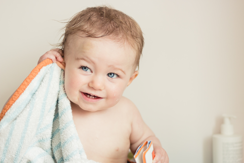 Baby after bathing, with towel and lotion