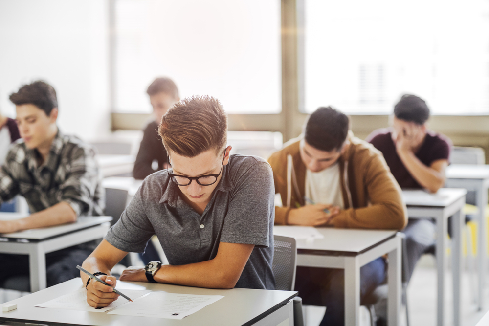 Group of high school students doing exam at classroom.
