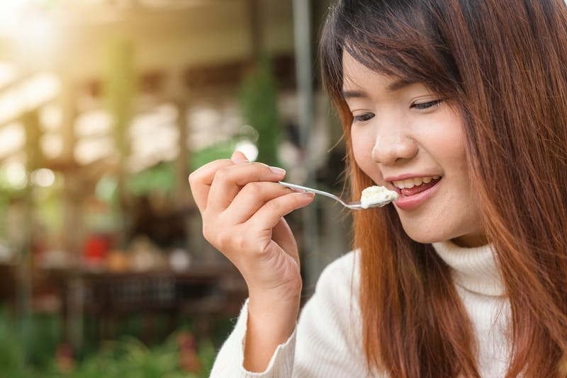 Young woman eating plain yogurt