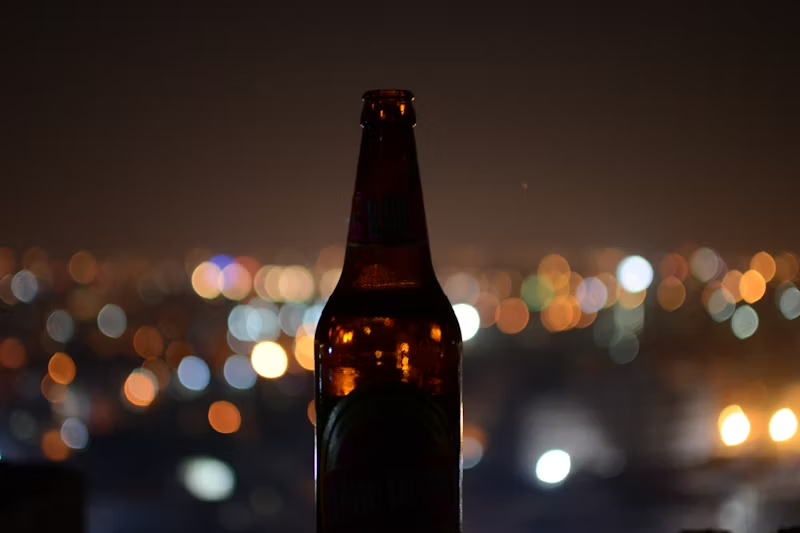 focused bottle of beer in front of a blurry city night landscape