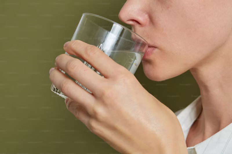 person drinking from a glass of water