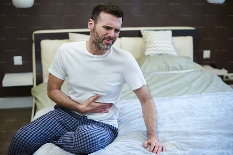 man on a bed experiencing constipation
