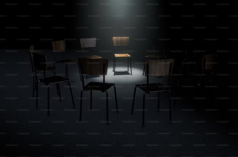 circle of empty chairs with a spotlight on one of them