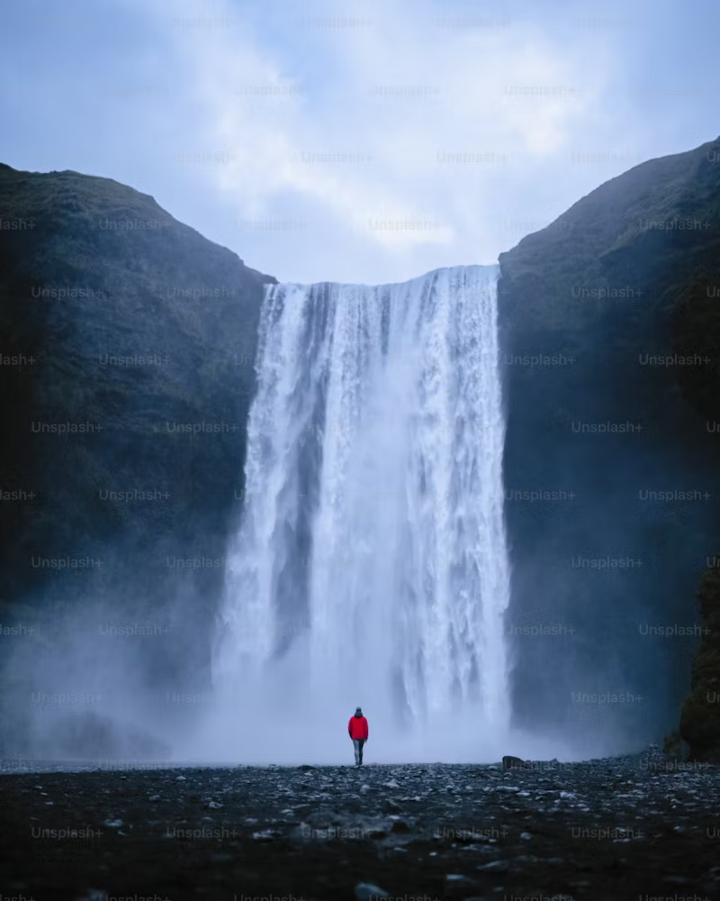 Person alone in front of a waterfall