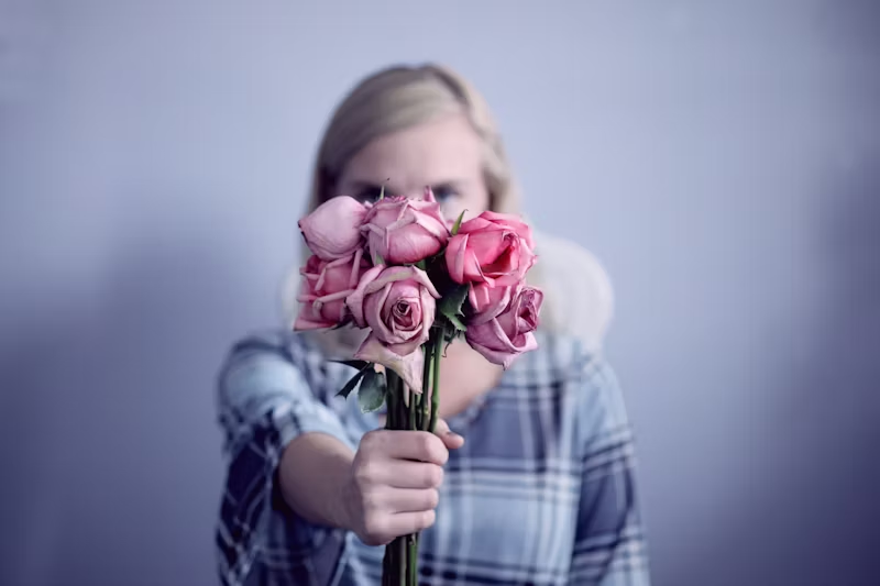 woman holding up wilted roses