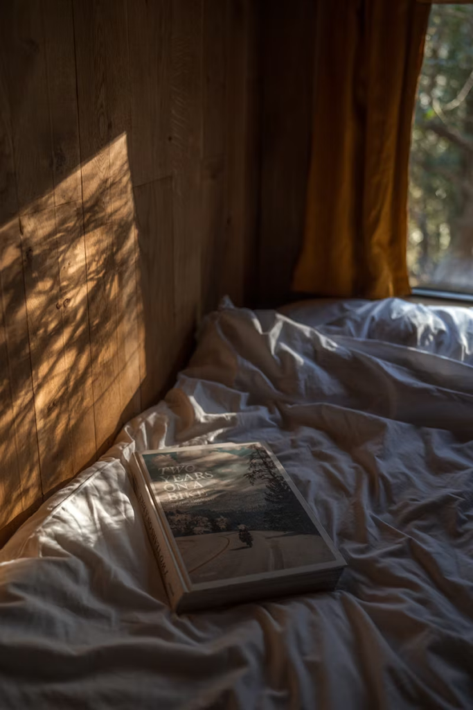 wood-walled bedroom with a book on the bed