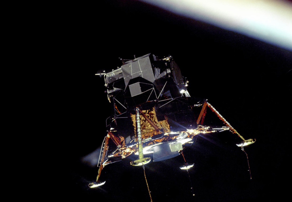 The Apollo 11 Lunar Module "Eagle", in a landing configuration is photographed in lunar orbit from the Command and Service Modules "Columbia." 