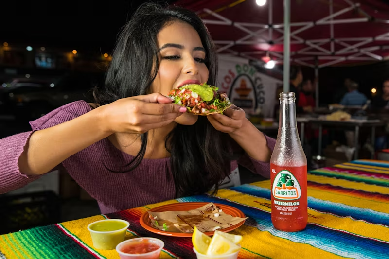A woman digging into an open-faced taco