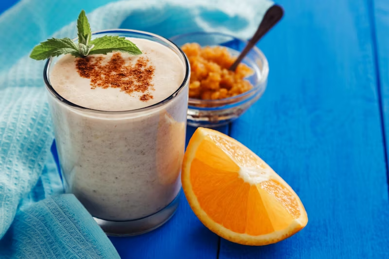 morning smoothie with cinnamon on top and an orange slice on the side