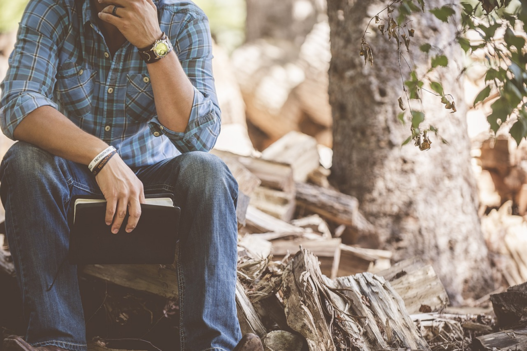 Man sitting in the forest with a book