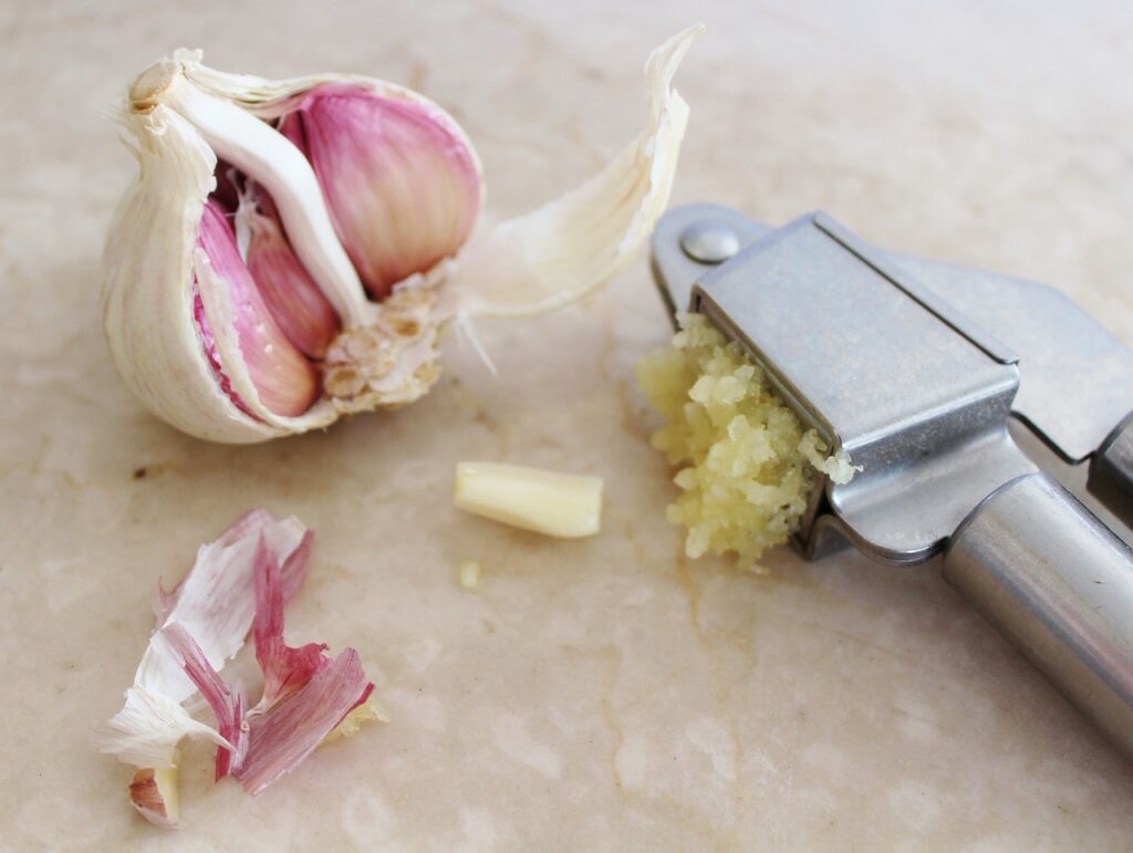 Garlic with a peeler. Quartz or marble background.