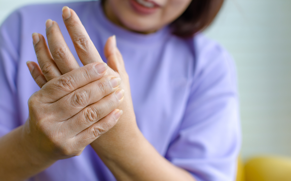 Woman using hand to hold other her palm with feeling pain, hurt and tingling. Concept of Guillain barre syndrome and numb hands disease.
