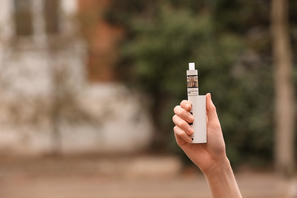 Female hand with modern vape mod outdoors