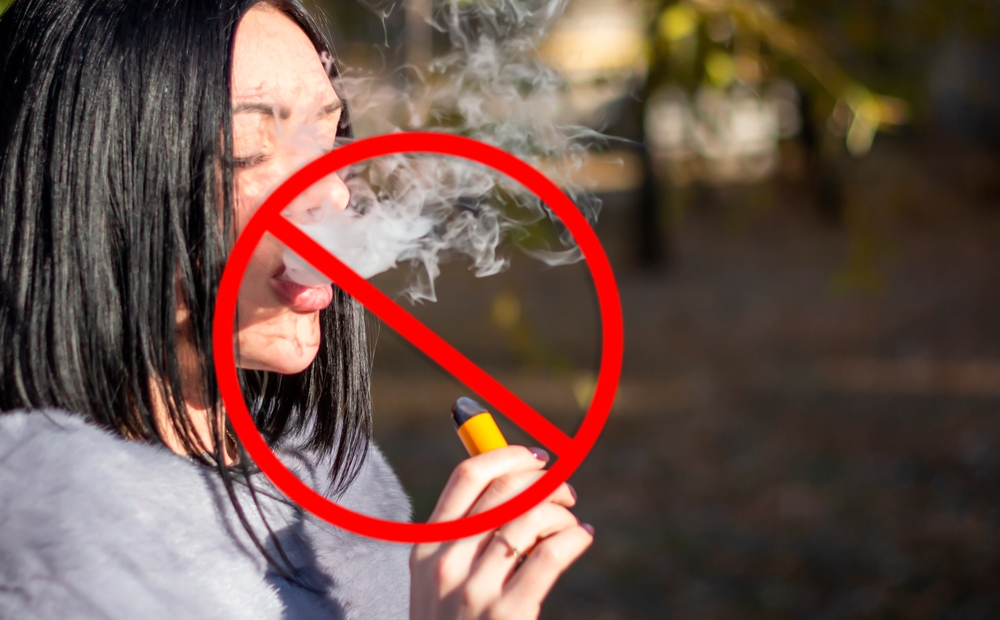 Vape ban. The girl smokes an electronic cigarette.