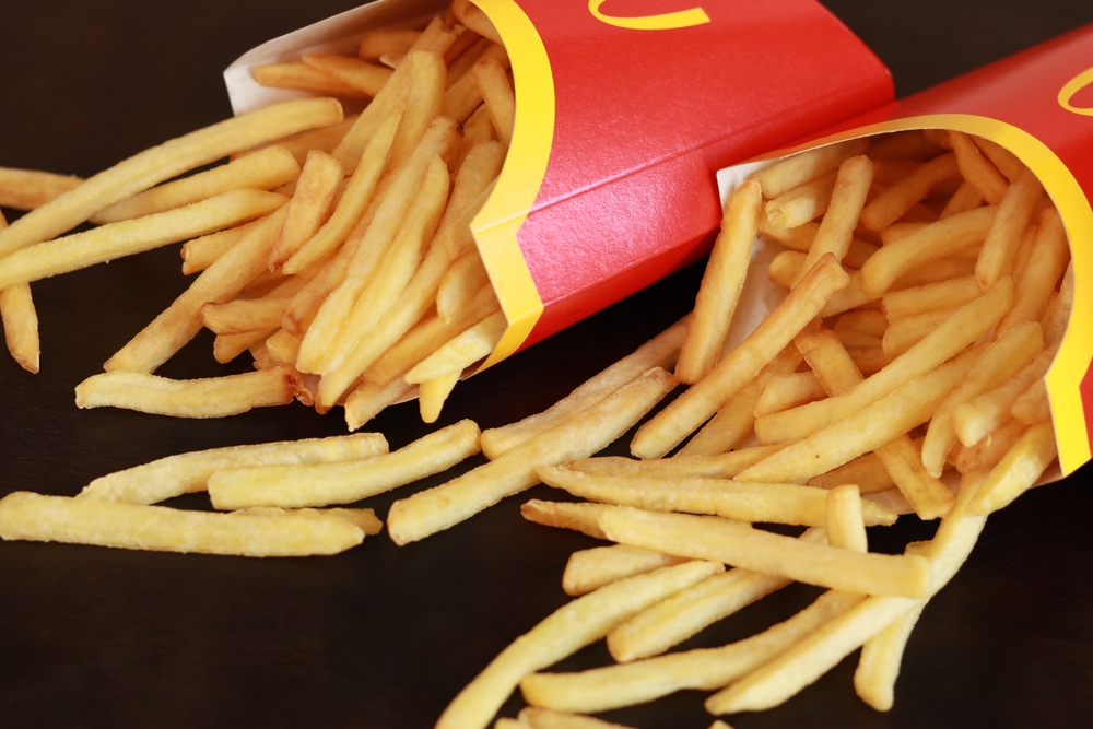 Kyiv, Ukraine - March 22, 2023: French fries scattered on the table on a dark wooden table. McDonald's Corporation is the world's largest fast food restaurant
