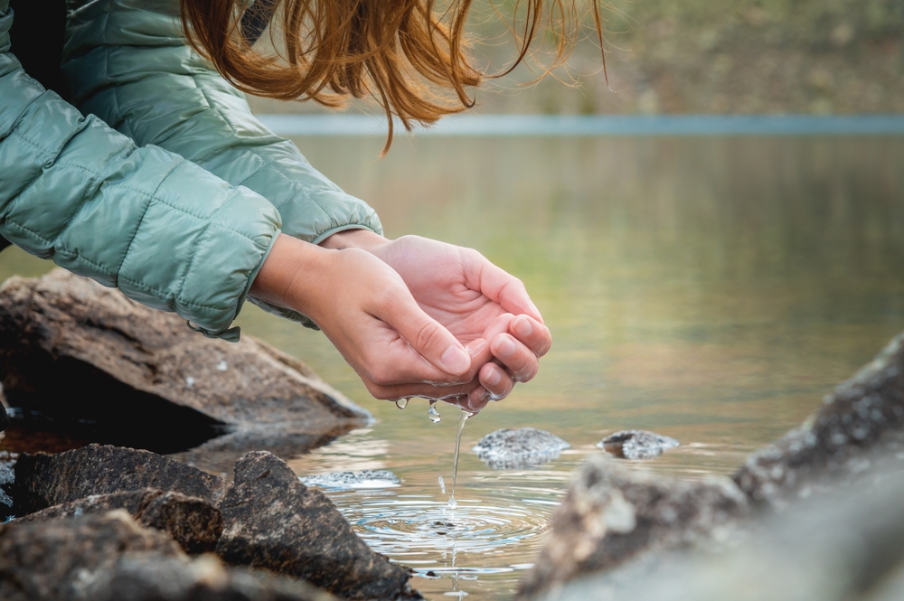 Close up, hands in the water from a glacial stream from the spring thaw. Clean refreshing drinking water in the forest. Pure water natural resources concept
