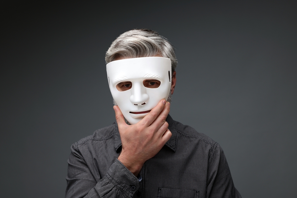 Multiple personality concept. Man in mask on dark grey background